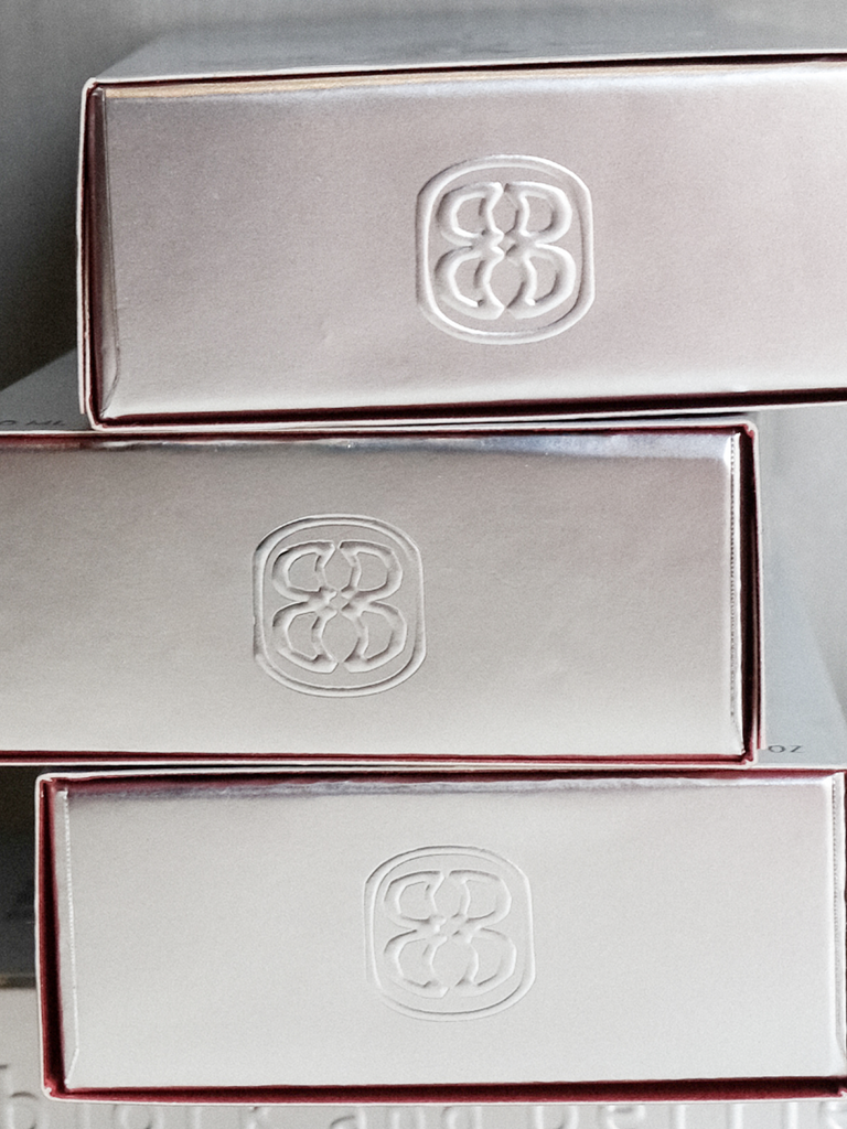 Stack of silver boxes with a logo on a reflective surface