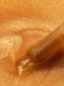 Close up of golden shimmering oil with a dropper, showing sparkling texture and rich amber color.