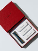 A red box with the top taken of revealing three perfumes, botanist, fjällsjö and white forest as well as a silver tube that states björk and berries. . 