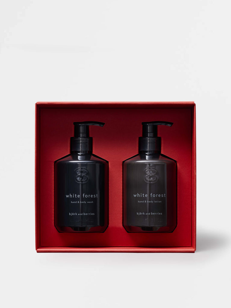 Two black bottles of 'White Forest' hand and body lotion in a red box on a white background.